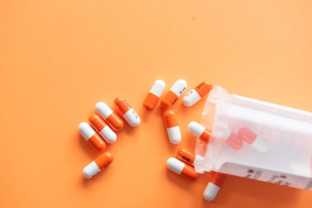 FDA Approves Repotrectinib for Lung Cancer Despite Significant Side Effects A patient holds a bottle of Augtyro pills while a doctor reviews medical scans on a monitor in a clinic.