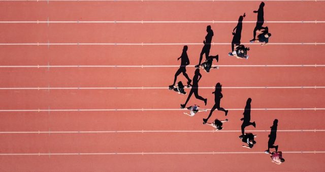 Running Community in Friesland Questions Safety After Fatal Collapse Runners cross the finish line at a crowded race event in a city plaza, with spectators cheering from the sidelines.