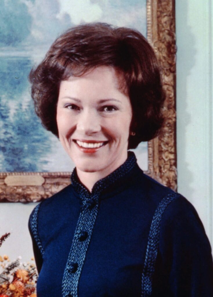 Rosalynn Carter smiles beside President Jimmy Carter at a 1977 mental health rally on the White House lawn.